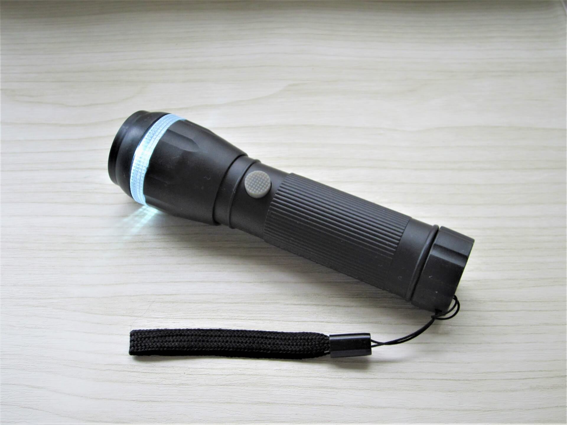 懐中電灯を持って暗闇を警戒する人のイメージ
